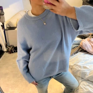 Ljusblå stickad tröja - Säljer en mysig ljusblå stickad tröja med en avslappnad passform. Tröjan har långa ärmar och en rund halsringning, perfekt för kyligare dagar. Den är enkel att matcha med jeans för en casual look.