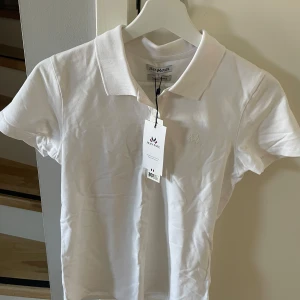 Vit pikétröja från Jean Paul - Säljer en klassisk vit pikétröja från Jean Paul. Tillverkad i bomull för en bekväm passform.