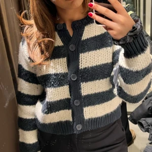 Randig kofta från Zara - Säljer en snygg randig kofta från Zara i mörkblå och vit. Koftan har knappar framtill och är stickad med långa ärmar.