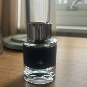 Montblanc Explorer Eau de Parfum - Säljer en elegant Montblanc Explorer Eau de Parfum. Flaskan har en stilren design med en blå textur och en silverfärgad kork. Perfekt för den som söker en sofistikerad doftupplevelse.