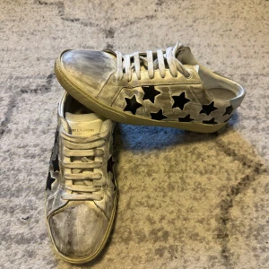 Saint Laurent skor  - Säljer dessa snygga, trendiga och unika saint Laurent skor med stjärnor. Skorna är i storlek 42. Skick 8,5/10. OG medföljer såsom dustbag och box. Defekter förekommer, creasing på båda skorna. Nypris runt 7000kr. Tveka ej på att skriva vid frågor eller funderingar. 