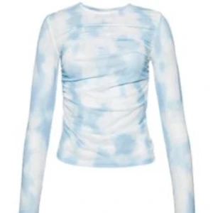 Blå och vit mesh topp från Ivyrevel - Säljer en snygg blå och vit mesh topp från Ivyrevel. Toppen har ett molnliknande mönster och långa ärmar. Perfekt för att lägga till en cool touch till din outfit. Tillverkad i polyester och elastan för en bekväm passform.