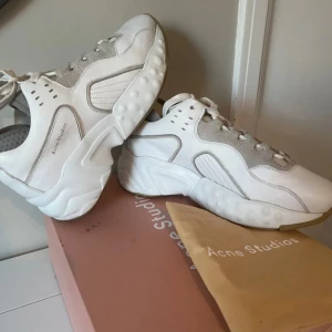 Vita sneakers från Acne Studios - Snygga vita rockaway Acne Studios sneakers med gråa detaljer och snörning. Skorna har en chunky sula och är tillverkade i en kombination av skinn och mocka.