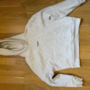 Grå hoodie från Axel Arigato - Säljer en super snygg grå hoodie från Axel Arigato med svart text på. Tjockt material och snygg luva. 