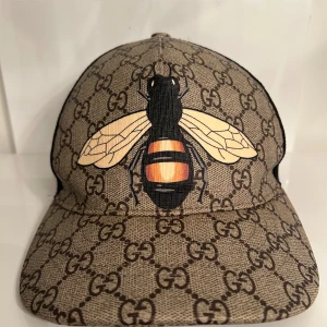 Gucci Bee Print - Gucci gg supreme bee cap. Gucci gg supreme bee cap. Beige/ebony canvas. Gg supreme with bee print. Adjustable hook & loop closure on back. Green/red web on back closure. Mesh back. 100% nylon. 100% canvas. Made in italy. Beige/ebony canvas. Gg supreme with bee print. Adjustable hook & loop closure on back. Green/red web on back closure. Mesh back. 100% nylon. 100% canvas. Made in italy.