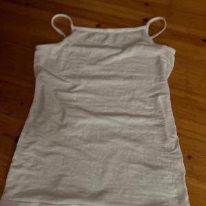 Vit linnetopp från H&M - Säljer en enkel vit linnetopp från H&M. Toppen har smala axelband och en enkel design som passar perfekt till sommaren. Den är tillverkad i ett mjukt och bekvämt material.
