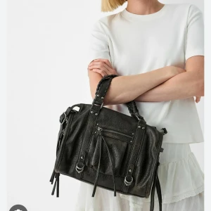 Svart axelväska med flätade handtag - Snygg svart axelväska. Väskan har flera praktiska fack och detaljer i metall. Perfekt den perfekta outfiten i sommar! Säljer efter som den inte kommer till användning🩷