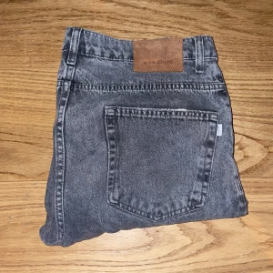 Grå jeansbyxor från Woodbird - Snygga grå jeansbyxor från Woodbird med en klassisk femficksdesign. De har en läderpatch med logotyp baktill och en stilren look som passar till många tillfällen.