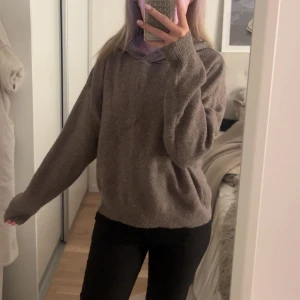 Brun stickad hoodie - Mysig brun stickad hoodie med långa ärmar. Perfekt för kyligare dagar med en avslappnad passform. Den har en klassisk huva och ribbade muddar vid ärmslut och nederkant.