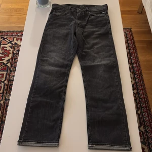 Svarta jeans från Replay - Snygga svarta jeans från Replay med klassisk femficksdesign. De har en knappgylf och är perfekta för en stilren look. Märket Replay är synligt på insidan av linningen.