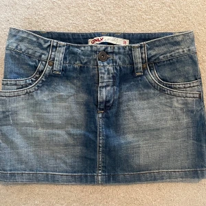 Blå jeanskjol från ONLY - Snygg blå jeanskjol från ONLY med klassisk femficksdesign och bälteshällor. Kjolen har en knapp och dragkedja framtill. Perfekt för en avslappnad stil.