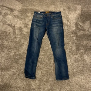 Blå jeans från Jack & Jones - Säljer ett par snygga blå jeans från Jack & Jones, modell Comfort/Mike. De har snygga slitningar på fram och baksidan. Helt ny skick, använda max 10 gånger. Köpta för 900 kronor.