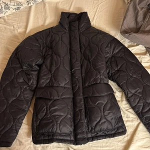Svart quiltad jacka från Esmara - Säljer en svart quiltad jacka från Esmara. Jackan har en hög krage och långa ärmar, aldrig använd då jag glömt bort den. Ursprungspris 400kr