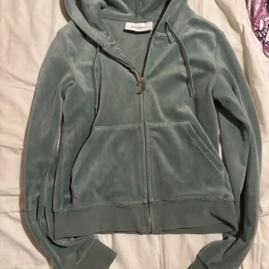 Grön hoodie från Juicy Couture - Säljer en snygg grön hoodie från Juicy Couture. Fint skick men har tappat båda metall knapparna i snöret.