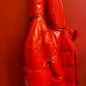Röd dunjacka från Moncler - Säljer en snygg röd dunjacka från Moncler. Jackan har en glansig finish och är utrustad med praktiska fickor med knappar. Perfekt för kyliga dagar när du vill hålla stilen. 🔥 jag kan inte se storleken så jag kommer lägga en random storlek 