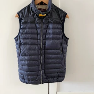 Mörkblå dunväst från Parajumpers - Säljer en snygg mörkblå dunväst från Parajumpers. Västen har en dragkedja framtill och är quiltad för extra värme. Perfekt för kyligare dagar och har en stilren design med märkets logga på baksidan.
