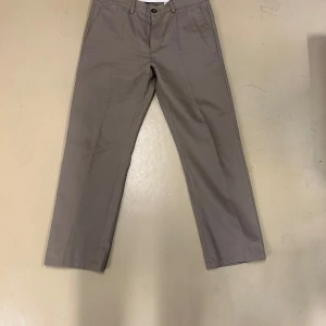 Beige chinos från Dressmann - Snygga beige chinos från Dressmann.. De har knappar och dragkedja framtill samt fickor både fram och bak.