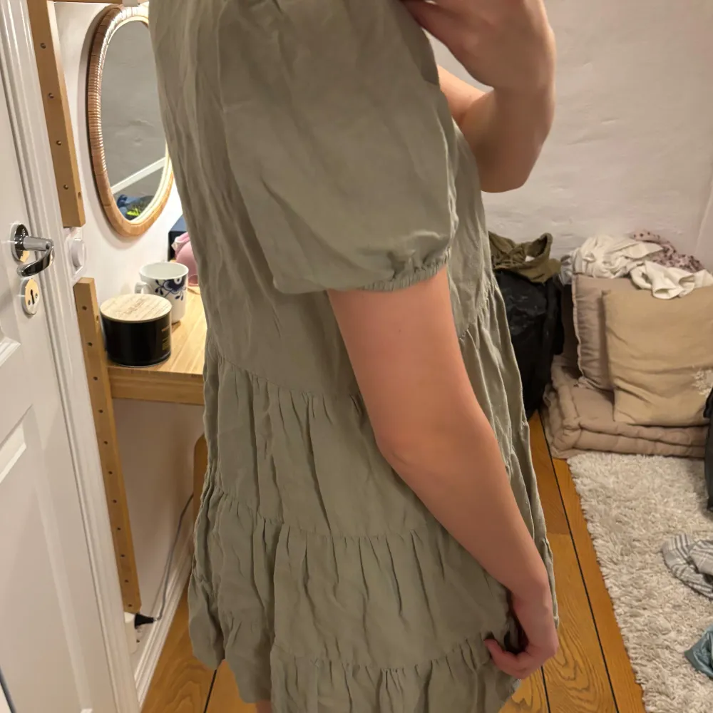 Säljer en söt grön klänning från Zara med korta puffärmar och volangdetaljer. Klänningen har en v-ringad hals och är perfekt för varmare dagar. Den är tillverkad i ett lätt och luftigt material. Den är även uppsydd vid axlarna men går enkelt att sprätta upp.. Mekot.