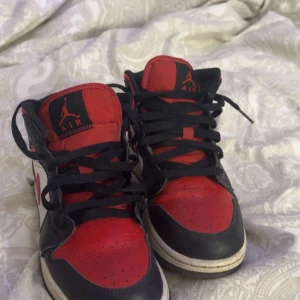 Nike Air Jordans i svart och rött - Säljer ett par klassiska Nike Air Jordans i svart och rött med vita detaljer. Skorna har snörning och den ikoniska Air Jordan-loggan på plösen. Perfekta för dig som älskar sneakers med stil.