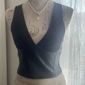 Svart ärmlös topp - Snygg svart ärmlös topp med djup v-ringning. Från ZARA. Använt bara en gång.