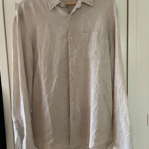 Beige linneskjorta från MNG MAN - Säljer en stilren beige skjorta i linne från MNG MAN. Skjortan har klassisk krage, bröstficka och knäppning framtill. 