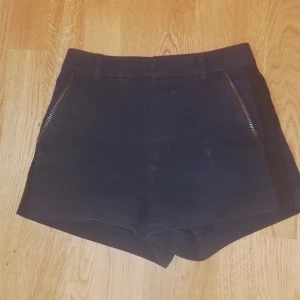 Svarta shorts från Zadig & Voltaire - Snygga svarta shorts från Zadig & Voltaire med dragkedjor framtill och bälteshällor. Klassisk design med fickor både fram och bak. Perfekta för en stilren och trendig look.