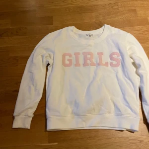 Vit sweatshirt med rosa text från Claudie Pierlot - Säljer en vit sweatshirt från Claudie Pierlot med rosa texten 'GIRLS' framtill. Tröjan har rund halsringning och långa ärmar. Perfekt för en avslappnad och cool stil. Märket finns bl.a. på NK. 500:- (Finns flera på Vestiare collective ute för högre pris)