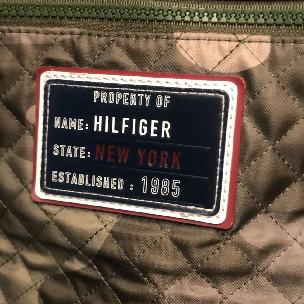 Säljer en quiltad ryggsäck från Tommy Hilfiger i camouflage-mönster. Väskan har både handtag och axelremmar, dragkedja framtill och en patch med texten 'Hilfiger New York'. Perfekt för dig som vill ha en cool och praktisk accessoar.. Laukut & Käsilaukut.