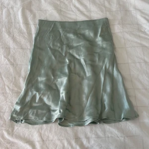 Ljusgrön satinkjol  - Säljer en ljusgrön satinkjol från H&M. Kjolen har en lätt utsvängd form 
