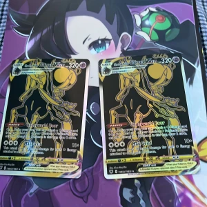 Pokémonkort Shadow Rider Calyrex VMAX - Två stycken Pokémonkort av typen Shadow Rider Calyrex VMAX från serien Brilliant Stars. Korten har en svart och gul design med holografiska detaljer och visar en stiliserad bild av Calyrex. Perfekt för samlare eller Pokémon TCG-spelare. Går att köpa en om man vill