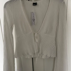 Vit ribbad knytblus  - Säljer en stilren vit ribbad blus från Gina tricot. Aldrig använd. Storlek xs.