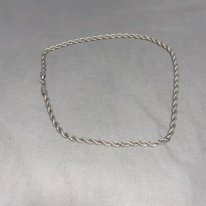 Silverfärgat halsband och armband - Snyggt set med ett silverfärgat halsband och matchande armband i tvinnad design. Perfekt för att ge en stilren touch till din outfit. 