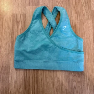 Turkos sport-bh från Gymshark - Säljer en turkos sport-bh från Gymshark med korsade axelband i ryggen. Bh:n har en tight passform och är perfekt för träning. Gymshark-logga framtill.🦋