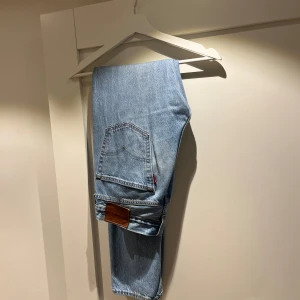 Blå jeansbyxor från Levis - Säljer ett par klassiska blå jeansbyxor från Levis. De har en straight passform och är tillverkade i jeansmaterial. Byxorna har en midwaist design och är perfekta för en avslappnad stil.