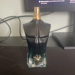 Parfym jean Paul  - Säljer en unik parfymflaska från Jean Paul Gaultier, formad som en manlig torso. Flaskan har en gradient från mörkblått till klart glas och en guldfärgad spraytopp. Perfekt för den som vill ha en stilren och iögonfallande parfymflaska i sin samling. Ungefär 75 ml kvar 
