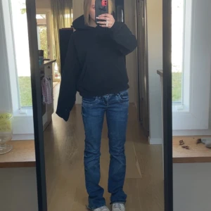 Blå jeansbyxor med normal passform - Säljer ett par klassiska blå jeansbyxor med normal passform och raka ben. Jeansen har fem fickor och stängs med dragkedja och knapp. Perfekta för en avslappnad stil.