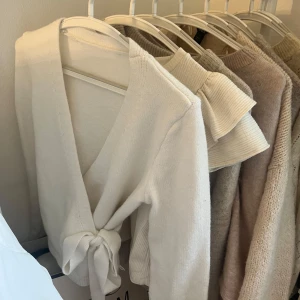 Vit omlottkofta med knyt - Superfin vit omlottkofta med knyt framtill. Mjuk och skön, perfekt att slänga på sig över en topp. Långärmad och i stickat material, passar till många olika outfits.