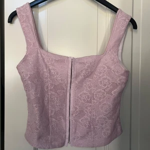 Ljusrosa spetskorsett - Säljer en ljusrosa korsett från Reclaimed Vintage. Toppen har breda axelband. Jätte fint skick💕💕