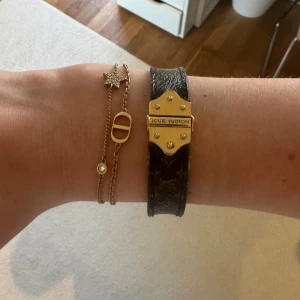 Louis Vuitton Nano Monogram Bracelet - Säljer ett Louis Vuitton Nano Monogram armband i brunt med klassiskt LV-mönster och guldfärgat spänne med logotyp. Nypris säljs den för 3000kr. Finns kvitto samt låda