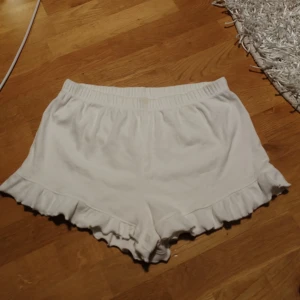 Vita volangshorts från Threadbare - Säljer ett par vita shorts från Threadbare med elastisk midja och volangdetaljer längs bensluten. Perfekta för varma dagar och riktigt sköna att ha på sig. Lätta att matcha med olika toppar. Hör av dig vid frågor🥰