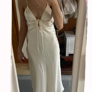 Benvit långklänning från Zara💓 Aldrig använt!! - Säljer en elegant långklänning i benvit färg från Zara. Klänningen har snörningsdetalj framtill och öppen rygg med knyt💗I storlek Xs🤍Den är helt ny och har aldrig använts! Jag köpte den för två månader sen och kunde inte skicka tillbaka den nu. Den hade lite för djup v-ringning och var inte precis den länden jag önskat, och därför säljer jag den!☺️