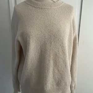 Beige stickad tröja från Gina Tricot - Mysig beige stickad tröja från Gina Tricot Young med rund halsringning och ribbade muddar vid ärmslut och nederkant. 