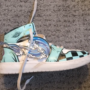 (REA!!!!!) Sneakers handmålade Jordan (lookalike) blåa vågigt mönster - Säljer ett par höga sneakers med handmålat motiv i blått, svart och vitt. Skorna har vågor på sidorna och schackrutigt mönster framtill. De har snörning och rund tå. Perfekta för dig som vill sticka ut med din stil! Handgjord och exklusiv. Storlek (Runt 40) Bra skick bara att dom är smutsiga men det går såklart att fixa! PÅ EXKLUSIV REA NU!