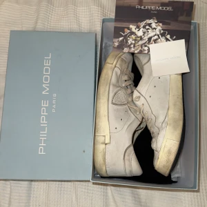 Vita Philippe Model sneakers - Säljer ett par vita Philippe Model skor med original box dustbag och med äkthetsbevis. Strl 42 passar även 43.  Har några synliga defekter samt så är det lite otydligt skrivet philippe model på ena skon!Nypris runt 3500-4000 hos oss endast 1749 passa på dessa skor är riktigt feta inför sommaren!