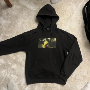 Svart hoodie med tryck - Säljer en svart hoodie med ett unikt tryck på framsidan. Tröjan har en klassisk passform som lutar mot slim fit, och en rymlig huva. Perfekt för en avslappnad stil. Köpt på carlings. Storlek Xs men passar S.