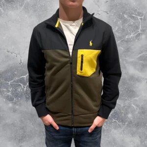 Ralph Lauren Zip Cardigan Svart  - •Ralph Lauren zip tröja ”Cardigan Kofta” svart/grön/gul. Skick: 8-9/10, Inga skador! Storlek: XS, Herr. Modell: 173 cm, 63 kg. Sitter bra på modellen på bild! Authentic: ✅. Nypris: 1 600 kr. Hör av dig vid frågor eller funderingar, mvh Hessler’s;)