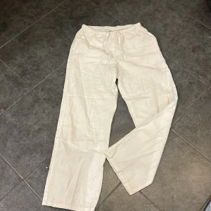 Vita linnebyxor från Gina Tricot - Säljer ett par vita linnebyxor från Gina Tricot med resår i midjan. Byxorna har raka ben och en avslappnad passform, perfekta för varma dagar. Lätta och luftiga i materialet.