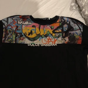 Svart t-shirt Dolce & Gabbana graffiti - Snygg svart t-shirt från Dolce & Gabbana med färgglatt graffitimönster över bröstet. Storlek xl men passar dom som har L