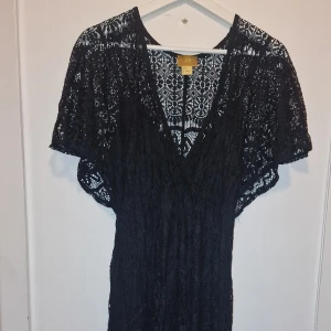 Svart spetsklänning från H&M - Supersnygg lång svart spetsklänning från H&M Gold Edition (Limited edition utgåva). Klänningen har ett genombrutet spetsmönster och markerad midja. Perfekt för dig som vill sticka ut med en elegant och bohemisk vibe. Passar XS/S