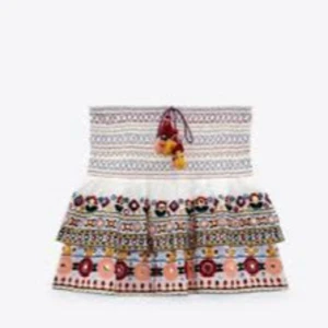 Zara sommarkjol - Superfin kortkjol i vitt med färgglada broderier och volang. Säljs inte längre och är därför ganska unik och svår att få tag på! Några trådar har lossnat lite men inget som syns om man inte kollar på nära håll. Fråga för fler bilder